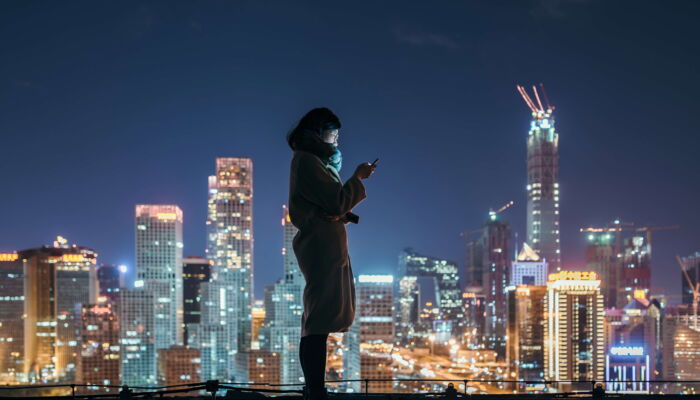 asian woman with smartphone in front of skyline
